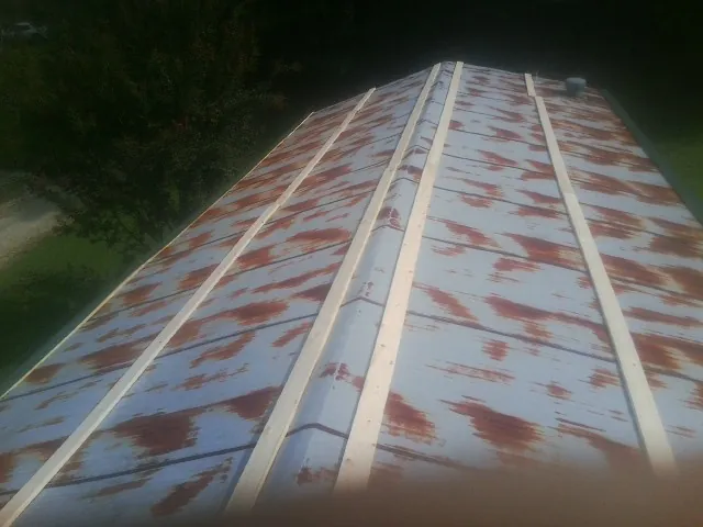 Rusted metal roof panels with new wood purlins before replacement — Storm Damage Roof Repair in Gentryville by Roofing Brothers