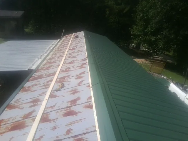 Old rusted panels beside newly installed green metal roofing — Wind Damage Roof Repair by Roofing Brothers in Gentryville