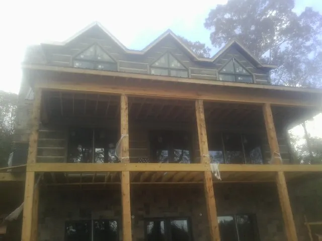 Dormers and porch framing on a large log home under construction — Roof Coating work by our crew in Gentryville