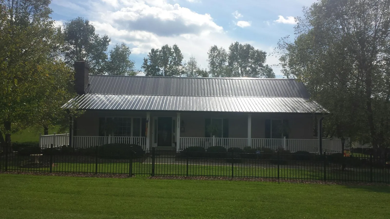 Gray metal roof on a brick ranch with a full width front porch — Gutter Guard Installation work by our crew in Gentryville