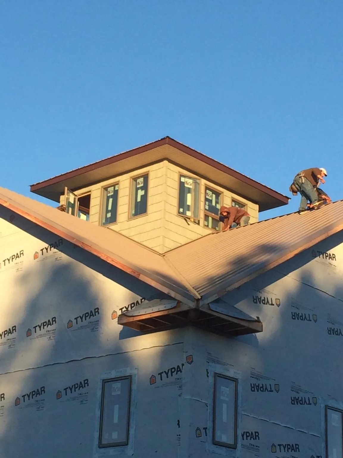 Roofers working around a rooftop cupola on a new metal roof at sunset — Roof Waterproofing in Gentryville by Roofing Brothers